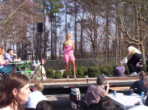 1986 Ford Bronco - A woman in a pink dress stands on a stage, holding some greenery, while an audience watches.