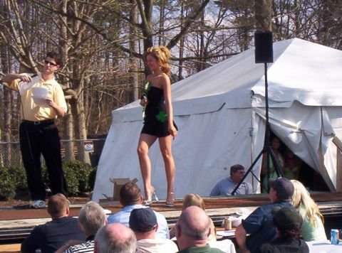 1986 Ford Bronco - A woman participates in a contest on a stage in front of a tent, with an audience seated before her.