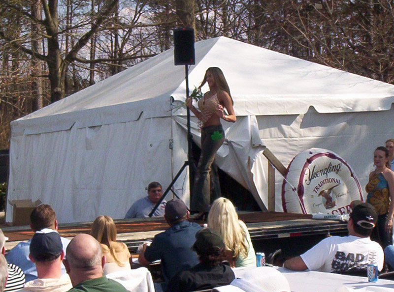 Woman on stage at outdoor event with tent and audience