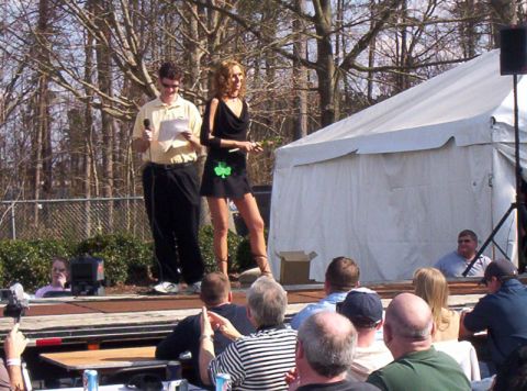1986 Ford Bronco - An outdoor event features a man and woman on a stage, with an audience watching and a large tent in the background.