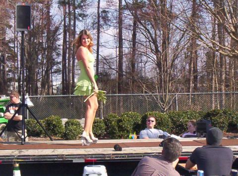 1986 Ford Bronco - Outdoor event with a woman on stage and spectators in the foreground.