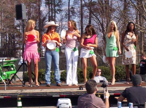 1986 Ford Bronco - A group of women are standing on a stage, possibly for a contest, with trees and a fence in the background.