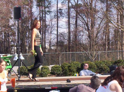 1986 Ford Bronco - A woman walks on a stage during an outdoor event, with spectators watching.