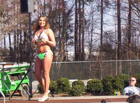 1986 Ford Bronco - A woman in a bikini stands on a stage with a green lift behind her.