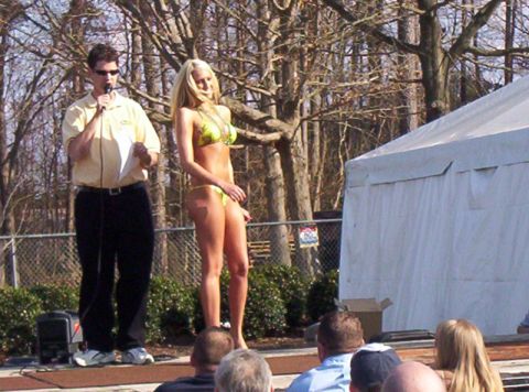 1986 Ford Bronco - A man holding a microphone stands next to a woman in a bikini on an outdoor stage during an event.