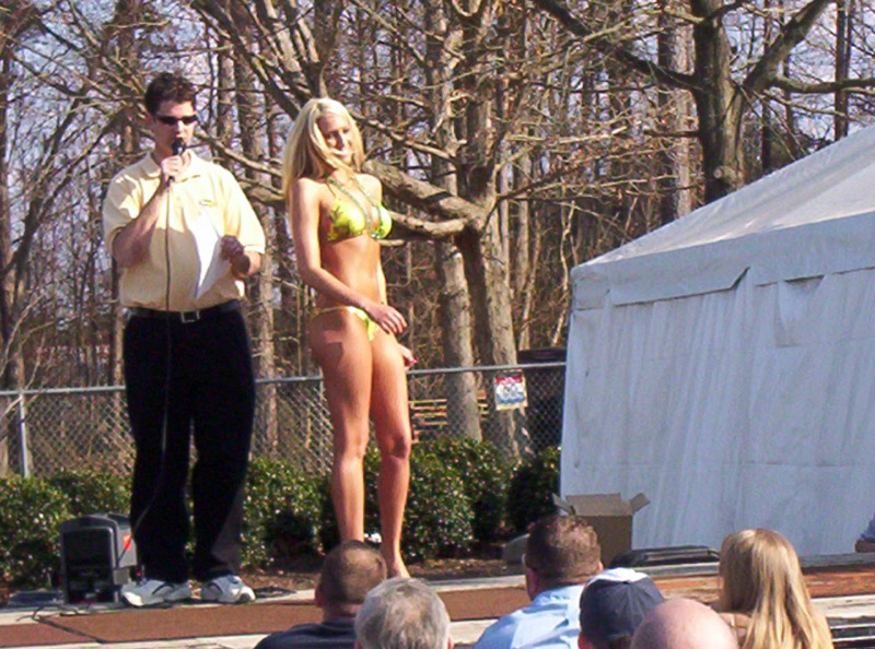 man with microphone next to woman in bikini on outdoor stage