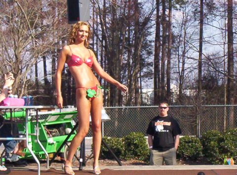 1986 Ford Bronco - A woman participates in a contest on an outdoor stage, with a spectator observing from behind a fence.