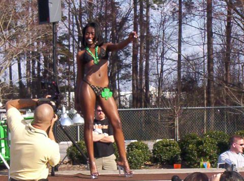 1986 Ford Bronco - Bikini contestant poses on an outdoor stage while a seated photographer shoots from the front.
