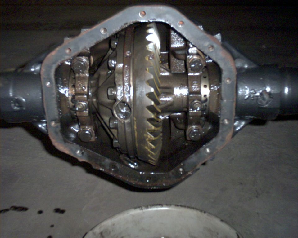 Axle differential with cover removed showing oiled ring gear and carrier bearing caps