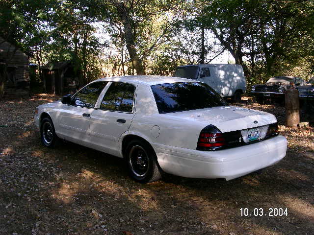 White 2001 Ford Crown Victoria parked outdoors with a van and another vehicle in the background