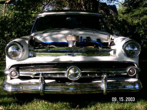 1954 Ford Crestline - Front view of a white 1954 Ford Crestline with its hood open, revealing the engine and chrome details.