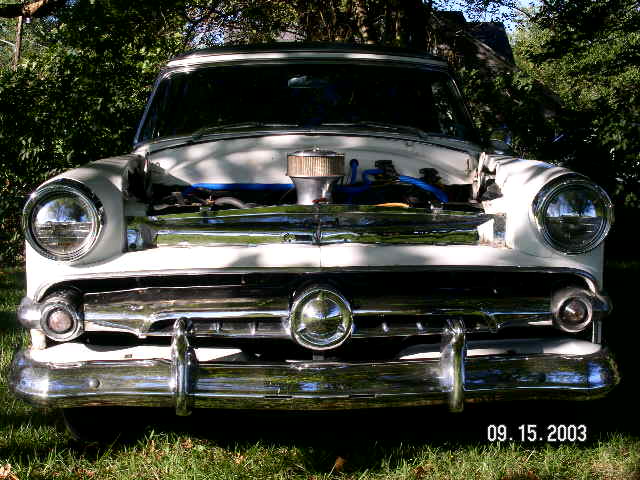 White 1954 Ford Crestline with hood open, showing engine and chrome grille