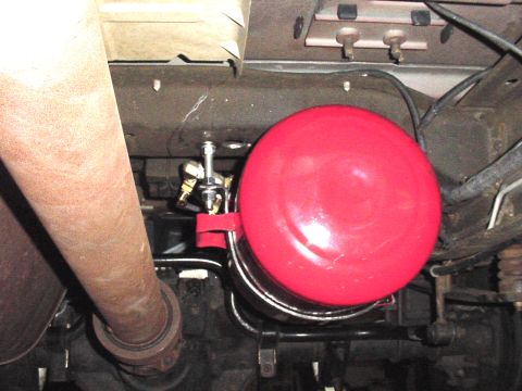 2002 Ford Excursion - A red air tank is mounted beneath the vehicle, near the exhaust pipe and suspension components.