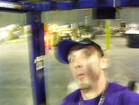 1986 Ford Bronco - A man in a purple shirt and blue cap takes a selfie in a warehouse setting.