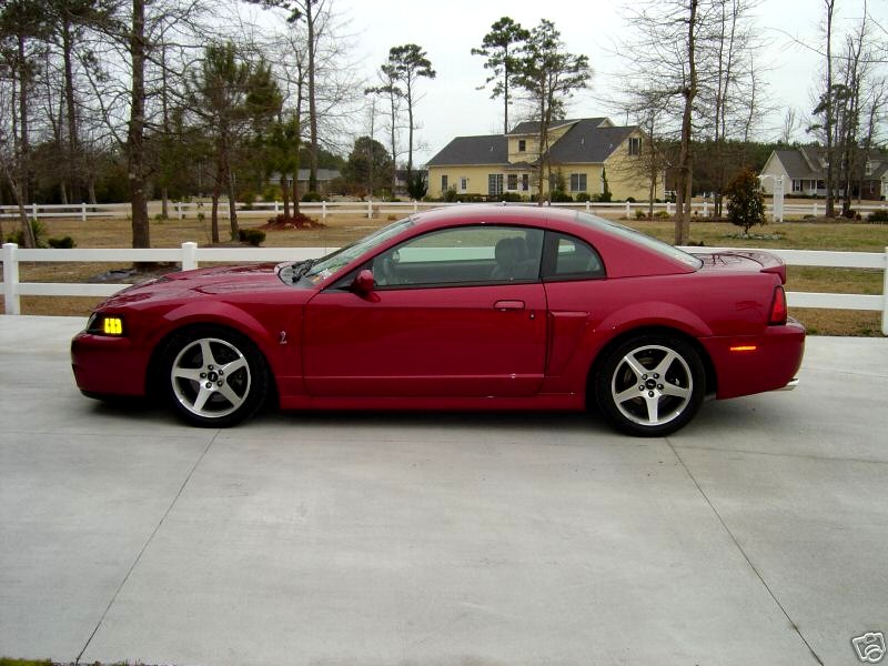 Red coupe with a spoiler parked on a concrete driveway