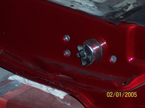1960 Ford Falcon - A close-up view of a car's interior door latch mechanism, a chrome knob and red painted metal.