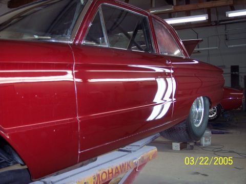 1960 Ford Falcon - Side view of a red 1960 Ford Falcon sedan undergoing work on a lift.