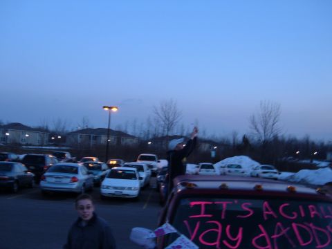 1995 Ford Bronco - Dusk parking lot shot over the cab of a dark red pickup whose rear window is painted in pink lettering reading "IT'S A GIRL! YAY DADDY", wi…
