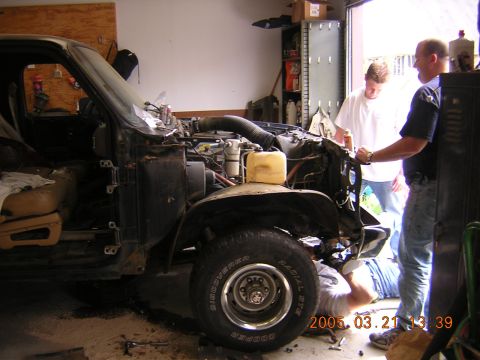 1986 Chevrolet Blazer - Three people are working on a truck that is partially disassembled in a garage setting.
