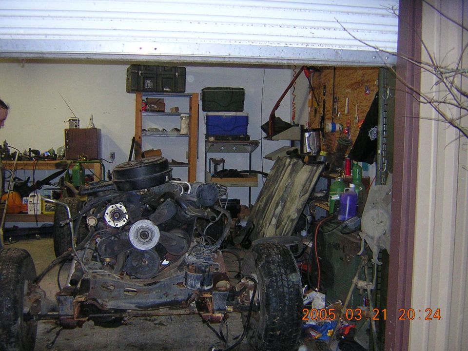 Vehicle chassis and engine in a garage, partially disassembled