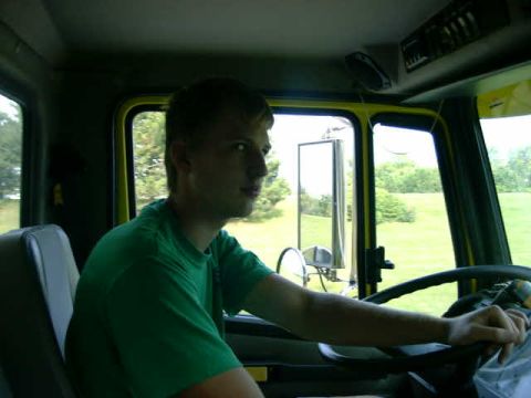 1999 Jeep Grand Cherokee - A person is driving a yellow truck on a sunny day, with trees and a field visible outside.