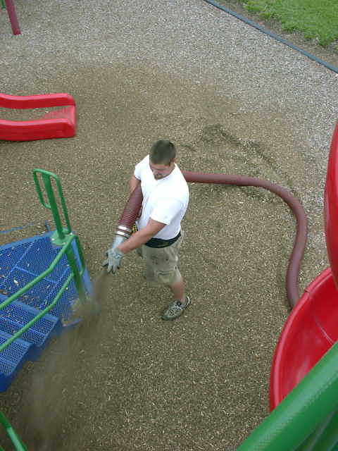 1999 Jeep Grand Cherokee - A man operates a blower hose on a playground with red slides and a blue play structure.
