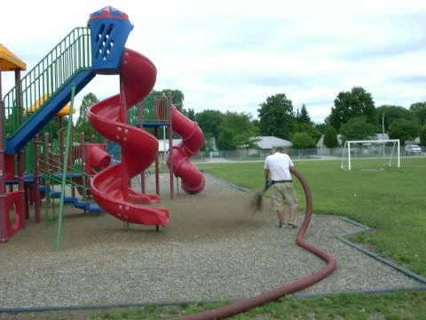 1999 Jeep Grand Cherokee - A person waters the ground near a large playground slide structure.