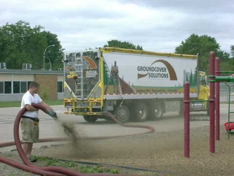 1999 Jeep Grand Cherokee - A man operates a blower hose connected to a truck, dispersing material onto the ground.
