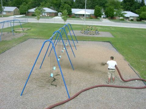 1999 Jeep Grand Cherokee - A person sprays a hose on a playground, with swings and a geodesic dome visible in the background.
