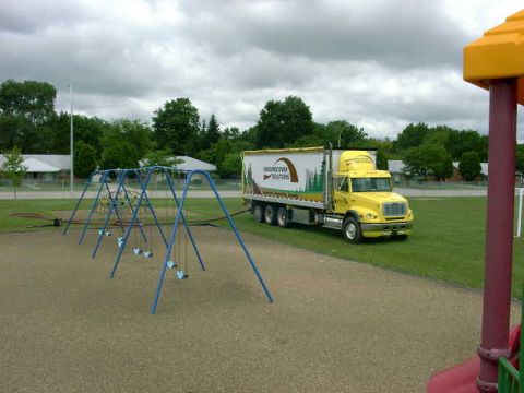 1999 Jeep Grand Cherokee - A yellow semi-truck is parked on the grass next to a playground on a cloudy day.