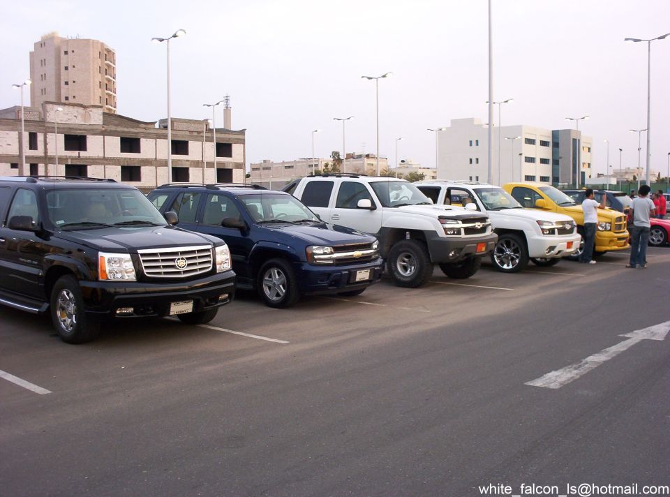 Lineup of black Escalade, blue TrailBlazer, white Avalanche and yellow Ram at a car meet