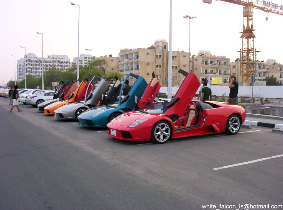 Several exotic sports cars parked in a row, all with their scissor doors open