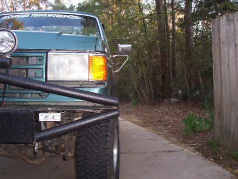 1989 Ford Bronco - Front view of a teal Ford truck with aftermarket bumper and lights, parked outdoors.