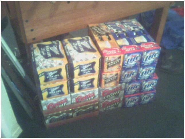 Stack of beer cases including Miller High Life, Coors Light, and Miller Lite, on a dark floor