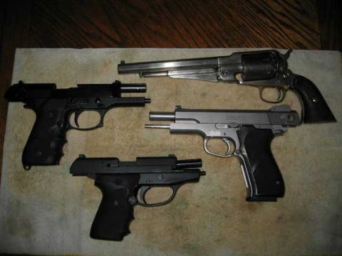 2002 Ford Taurus - A collection of four handguns, including a revolver and three semi-automatic pistols, are displayed on a textured surface.