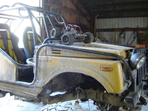 1989 Ford Bronco - A yellow off-road vehicle sits in a barn, with a toy car on its hood.