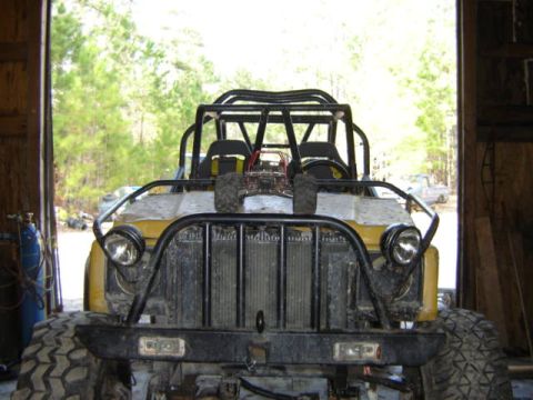 1989 Ford Bronco - This heavily modified off-road vehicle features a prominent roll cage and large tires, obscuring its original make and model.