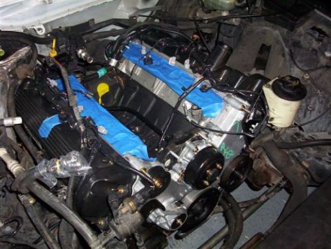2000 Ford Crown Victoria - Engine bay during work, with parts of the engine covered in blue tape.