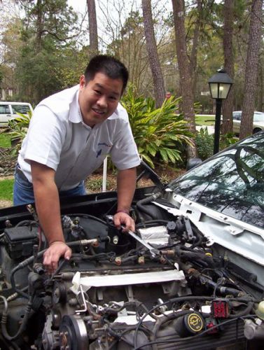 2000 Ford Crown Victoria - A man works on a car's engine bay, with the SuperMotors.net logo visible in the lower right corner.