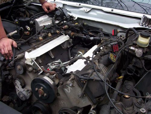 Engine bay during a swap with pulleys, wiring, hoses and white paper draped over intake