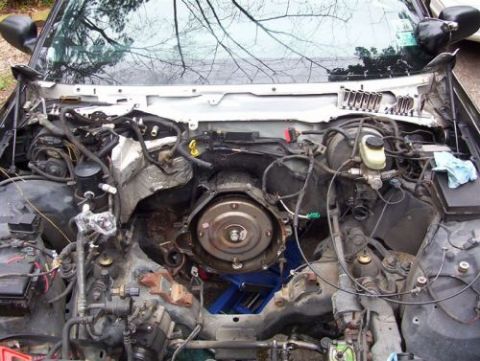 2000 Ford Crown Victoria - The engine bay of a car with the transmission removed, revealing the engine block and various hoses and wires.