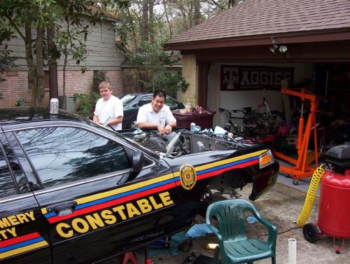 Black Constable-lettered Crown Victoria sedan with hood open during engine work