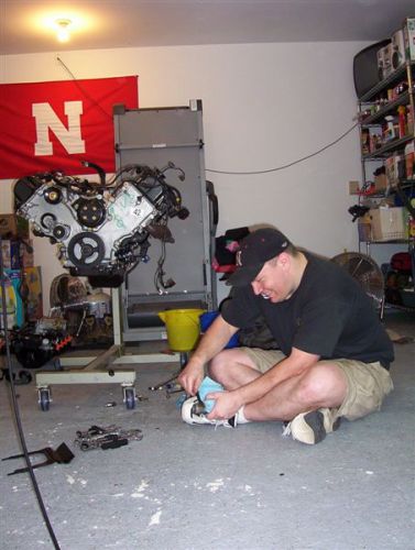 2000 Ford Crown Victoria - Man cleans an engine on a stand in a garage with a Nebraska flag in the background.