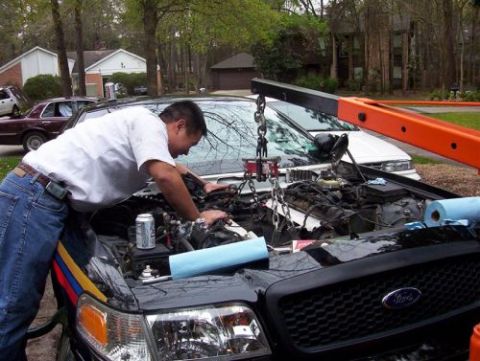 2000 Ford Crown Victoria - Engine removal in progress on a 2000 Ford Crown Victoria, with a second vehicle visible.