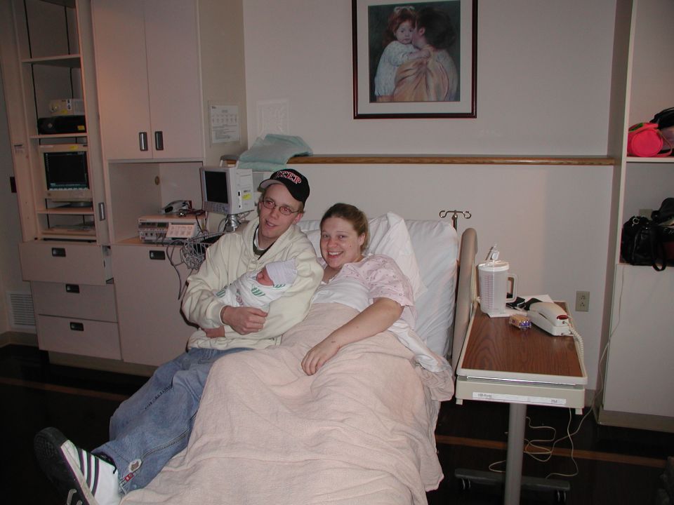 Family posing in a hospital room with a newborn baby