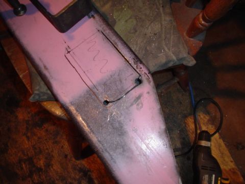 1981 Ford Bronco - A pink-primered steel bumper clamped on a sawhorse with a rectangular cutout scribed and scribbled on its face, corner starter holes alread…