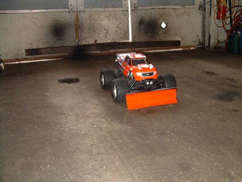 1994 Ford Bronco - A remote-controlled truck with oversized tires and a front-mounted snow plow sits on a concrete floor.