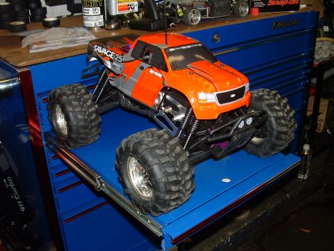 1994 Ford Bronco - This remote control monster truck features large, aggressive tires and a bright orange body, sitting on a blue toolbox.