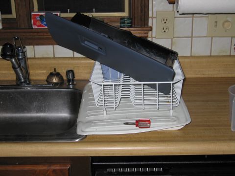 1991 Ford Crown Victoria LTD - A car dashboard part is placed in a dish rack to dry next to a kitchen sink.