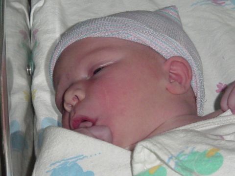 1989 Ford Bronco - A newborn baby sleeps peacefully, swaddled in a blanket and wearing a hospital cap.